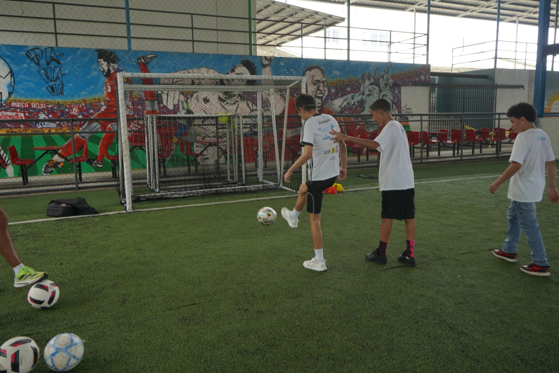 Niños entrenando con balones en la cancha